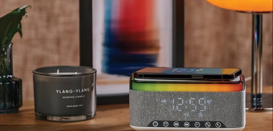 Bluetooth speaker with wireless charger and clock beside a scented candle